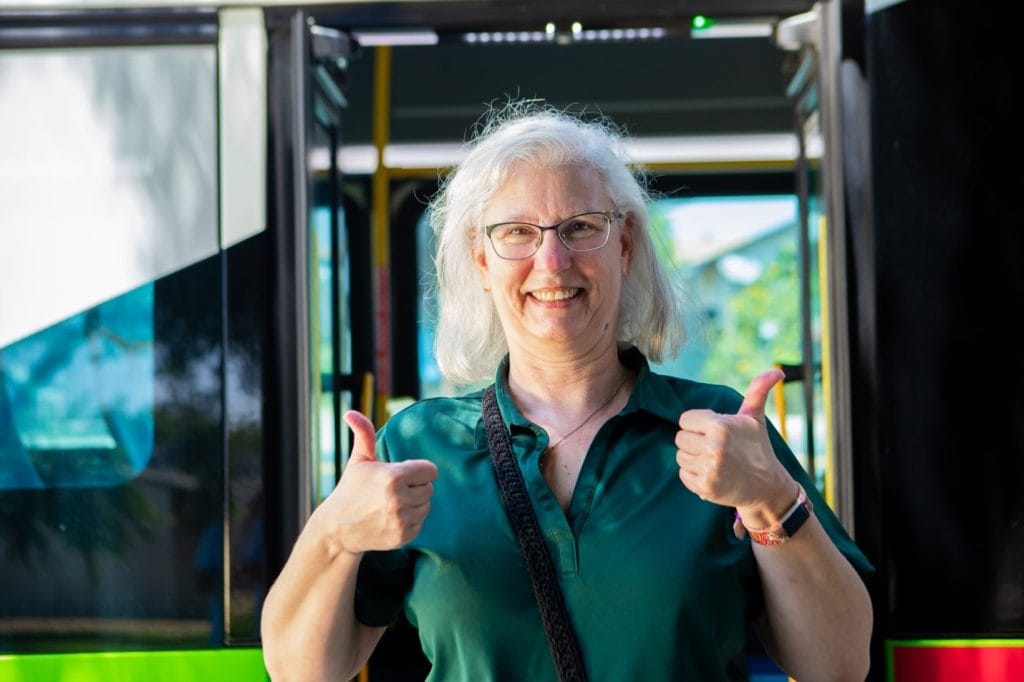 Senior woman at bus entrance with thumbs up